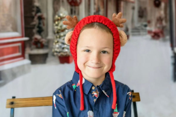 Young boy smiles at the camera in a Christmas scene