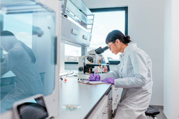 A scientist in a lab looking through a microscope