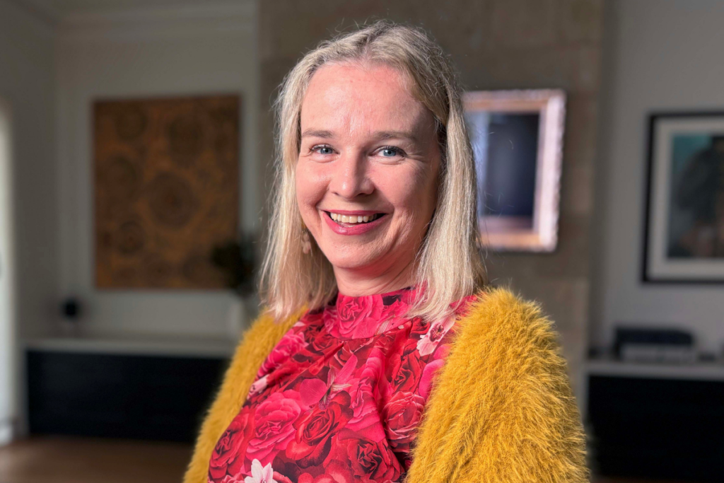 Woman in her 40s wearing a bright outfit smiles at the camera