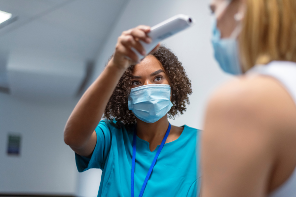 A nurse checks the temprature of her patient