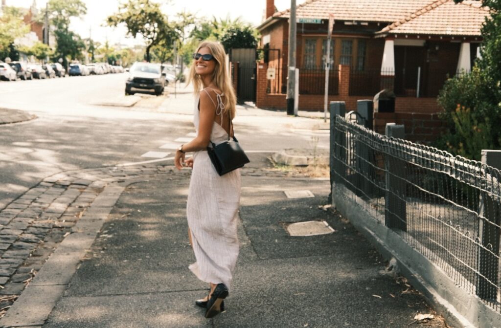 Kelly walking and smiling in the street.